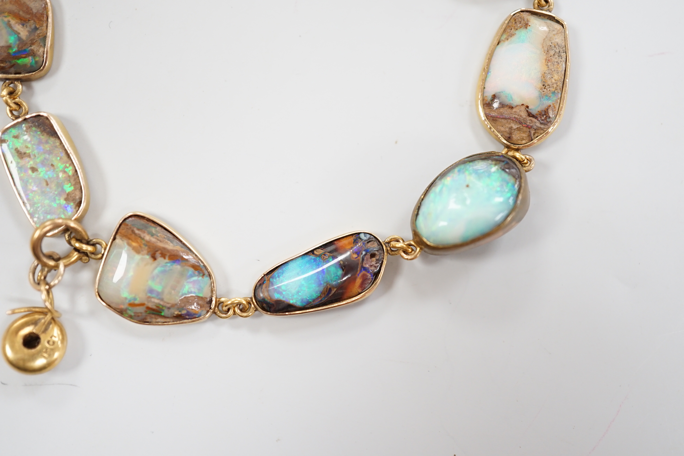 An early 20th century yellow metal and opal set bracelet, of various shapes and hung with central 15ct and diamond chip set charm, 21cm, gross weight 15 grams.